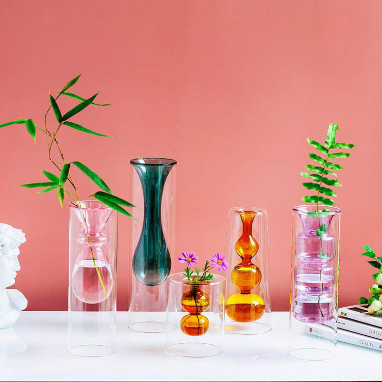 Five colourful sculptural bud vases against coral background
