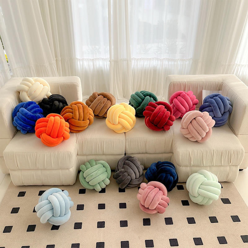 Plush knot cushions in many colours on sofa