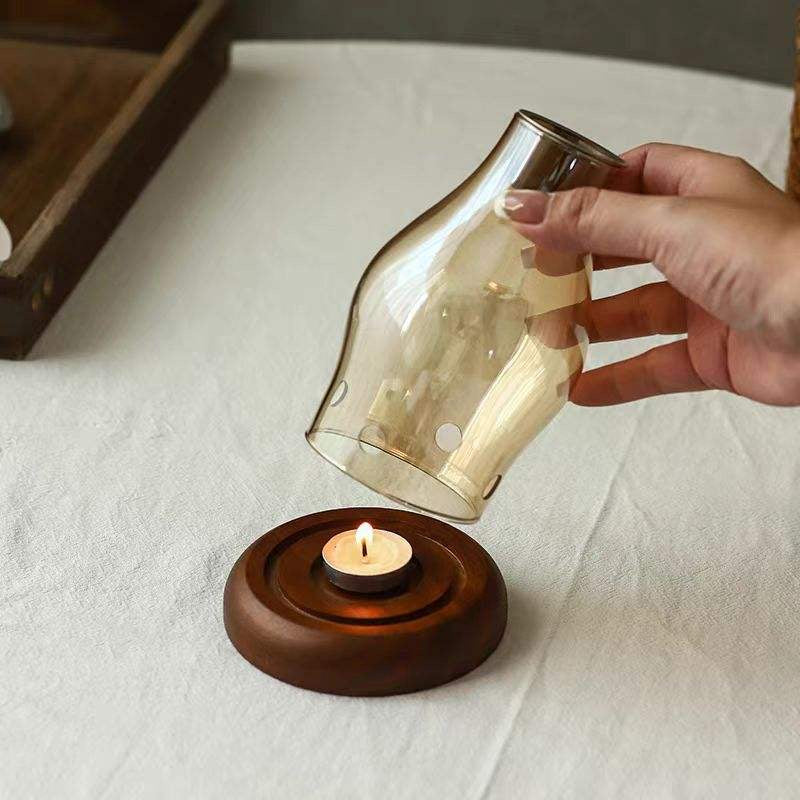 Glass shade being placed over tealight on wooden candle holder