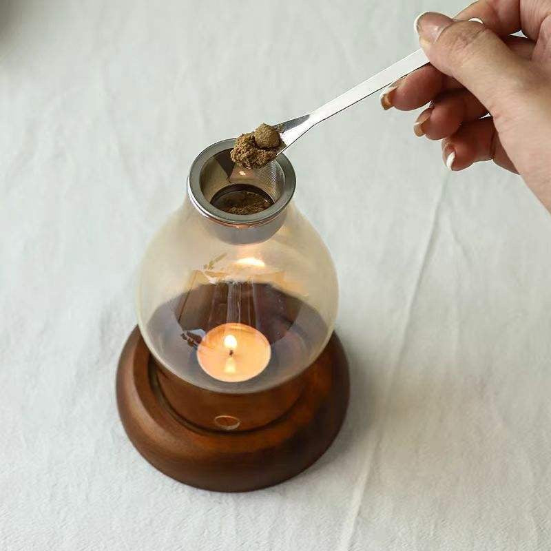 Glass candle and incense holder with wooden base in use