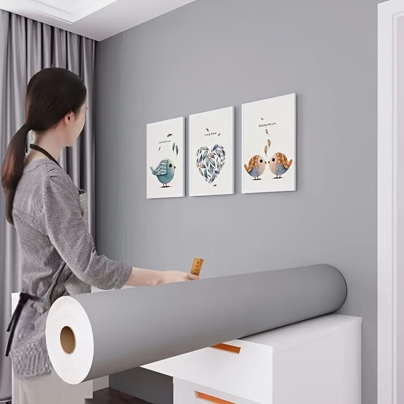 Self-adhesive wallpaper roll being applied to an interior wall